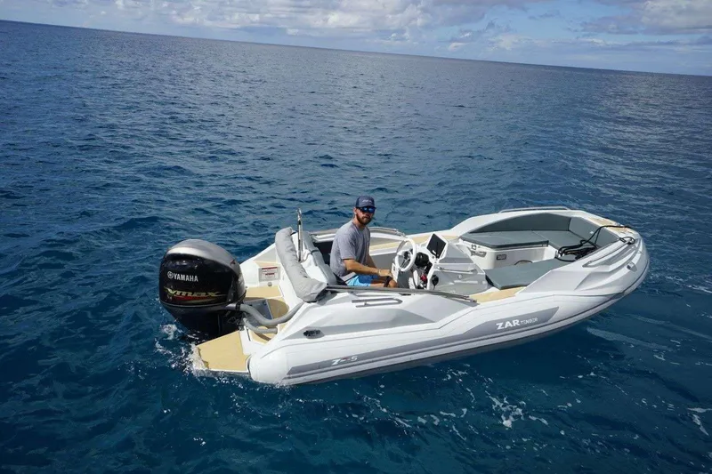 Relentless Yacht Photos Pics Man steering a ZAR mini boat with Yamaha engine on open sea.