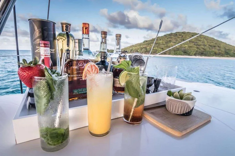 Relentless Yacht Photos Pics Cocktails and spirits on Sunreef Sail 60 yacht, 2020, with ocean and island backdrop.