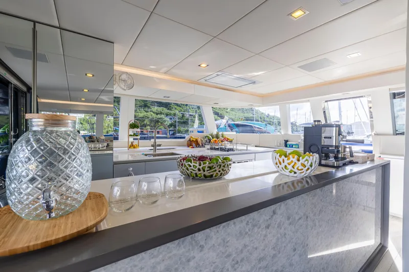 Relentless Yacht Photos Pics Luxurious Sunreef Sail 60 yacht interior, featuring modern kitchen with fruit bowls and glassware.