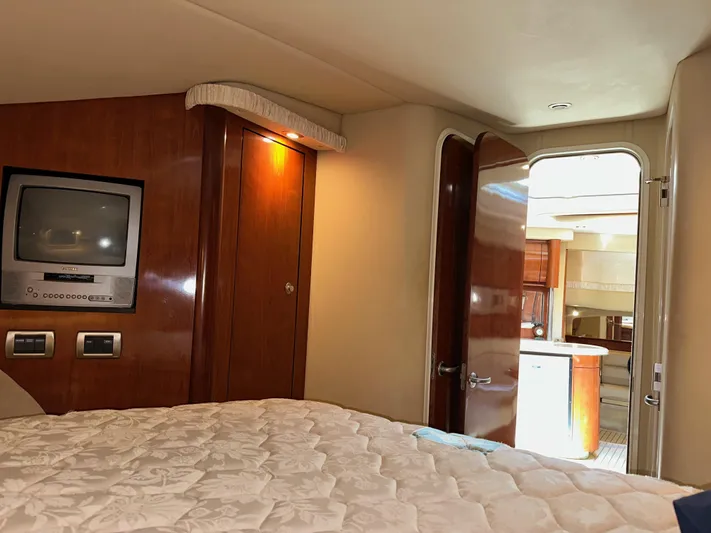 Alibi Yacht Photos Pics Interior cabin of 2004 Sea Ray 420 Sundancer with bed, TV, and wooden cabinetry.