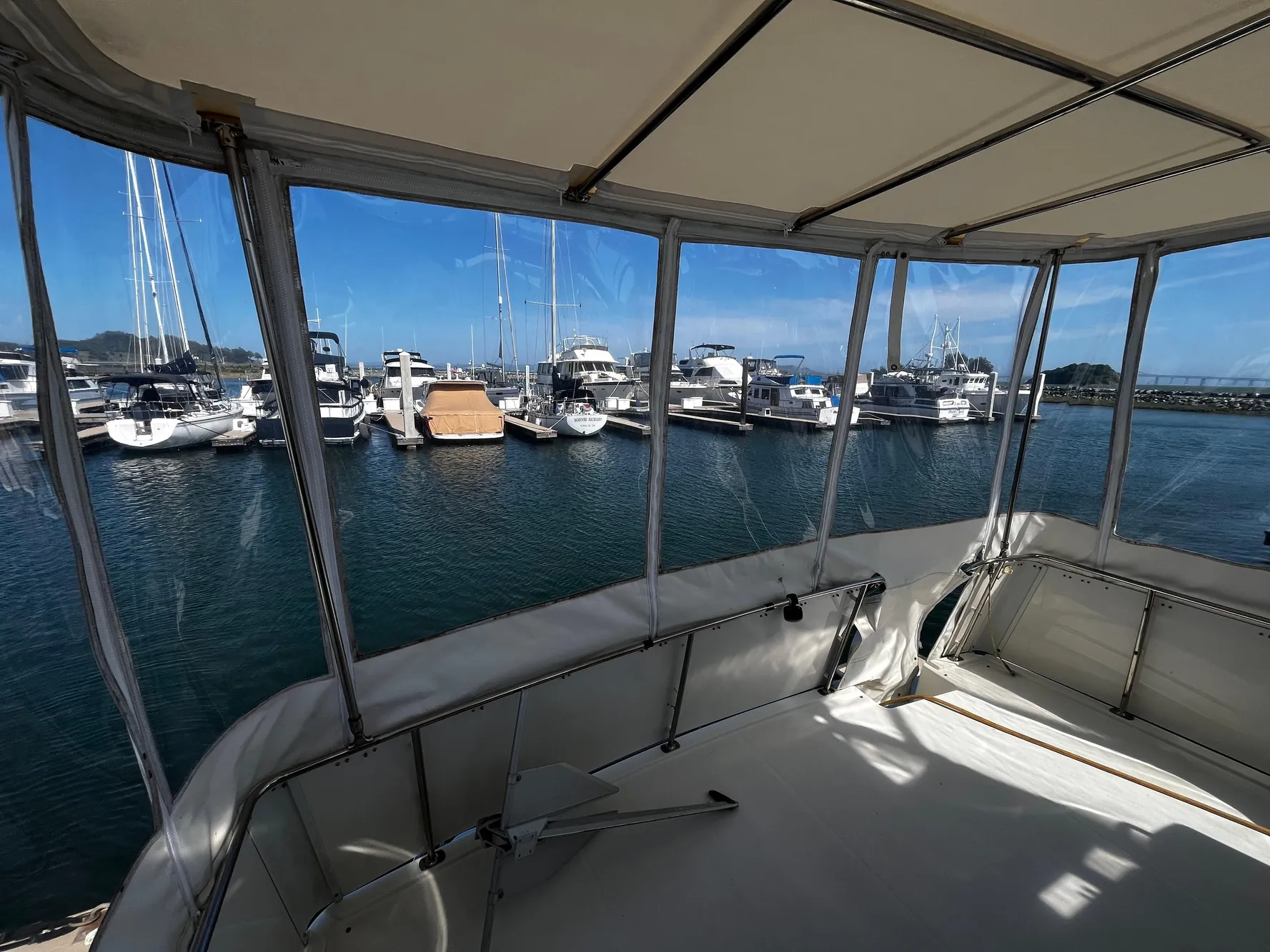 1996 Carver 325 Aft Cabin yacht interior with marina view, featuring clear skies and docked boats.