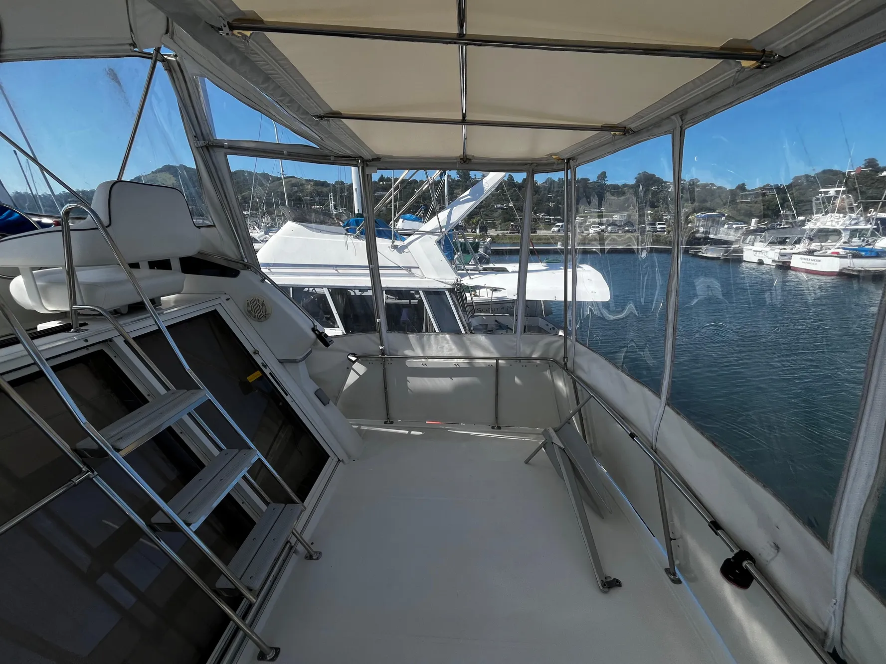 1996 Carver 325 Aft Cabin boat interior with marina view, featuring enclosed deck and seating.