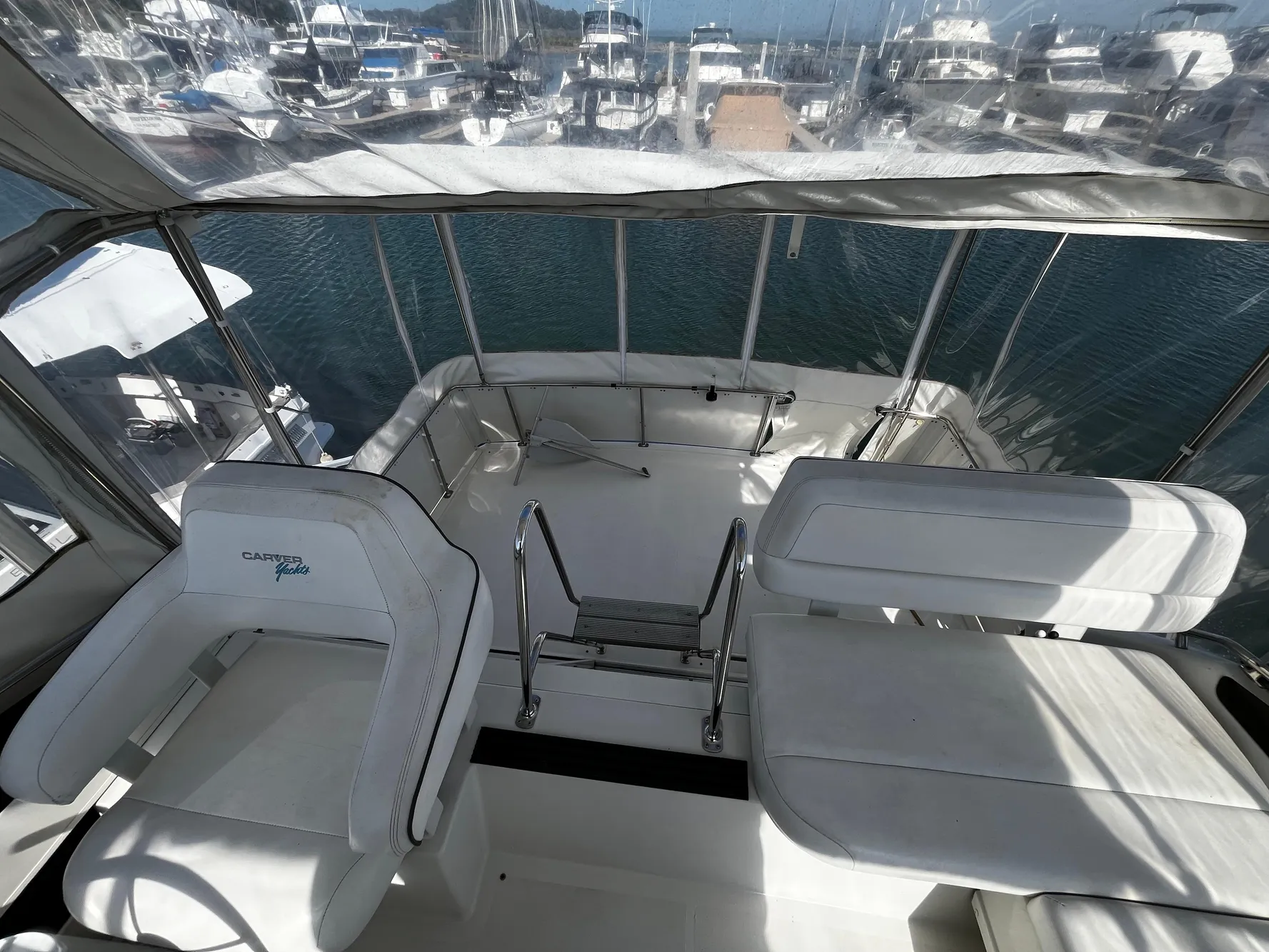1996 Carver 325 Aft Cabin yacht interior with white seating and marina view.