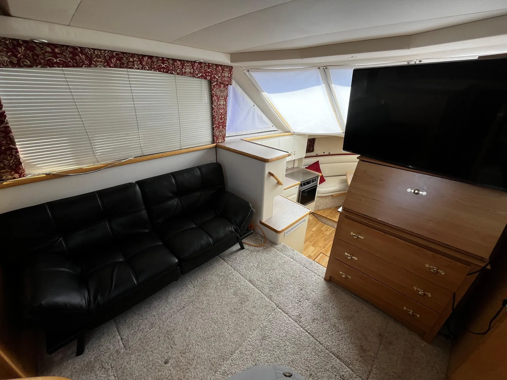 1996 Carver 325 Aft Cabin interior with black sofa, TV, and wooden cabinetry.