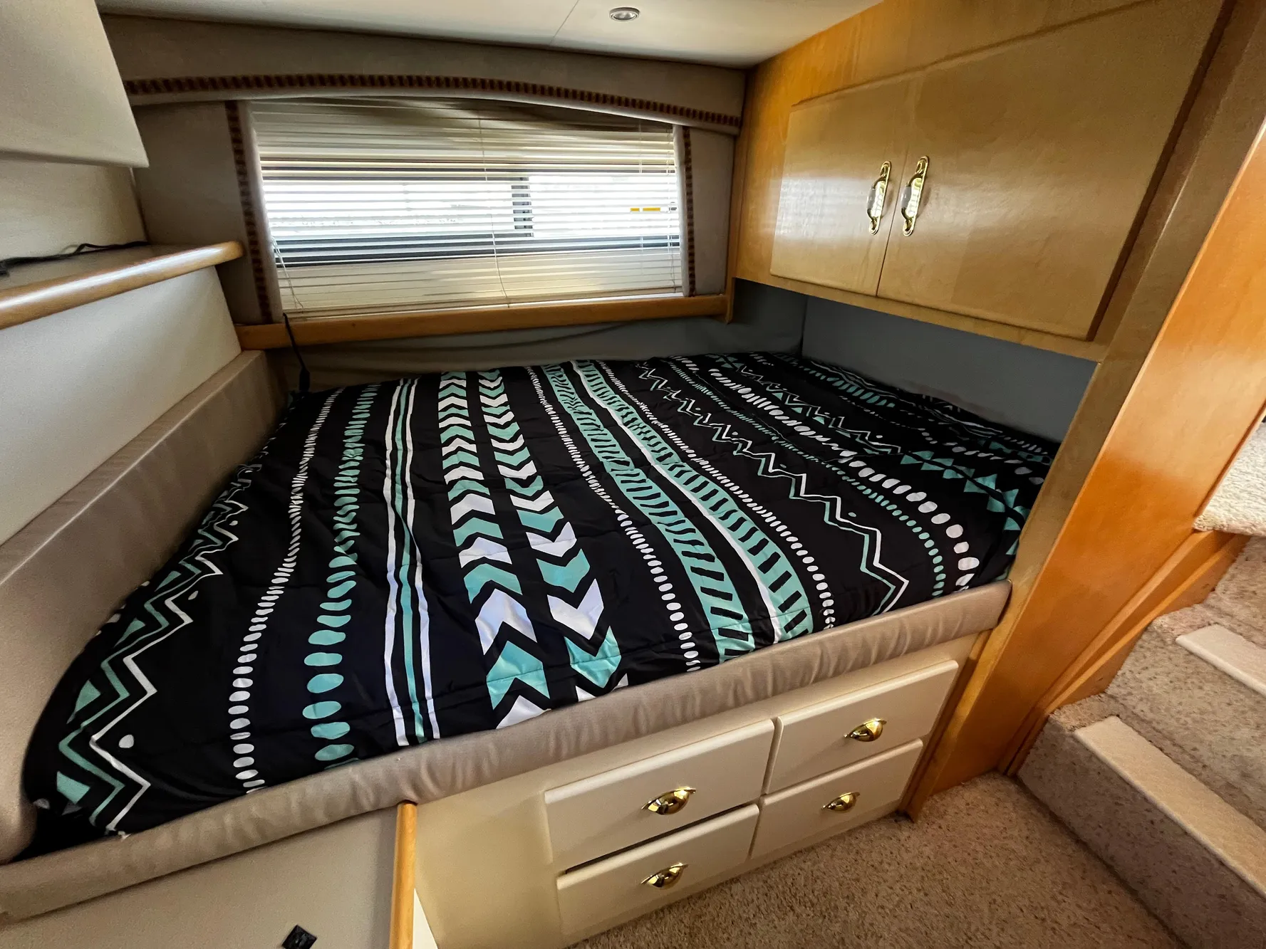 1996 Carver 325 Aft Cabin bedroom with patterned bedding and wooden cabinetry.