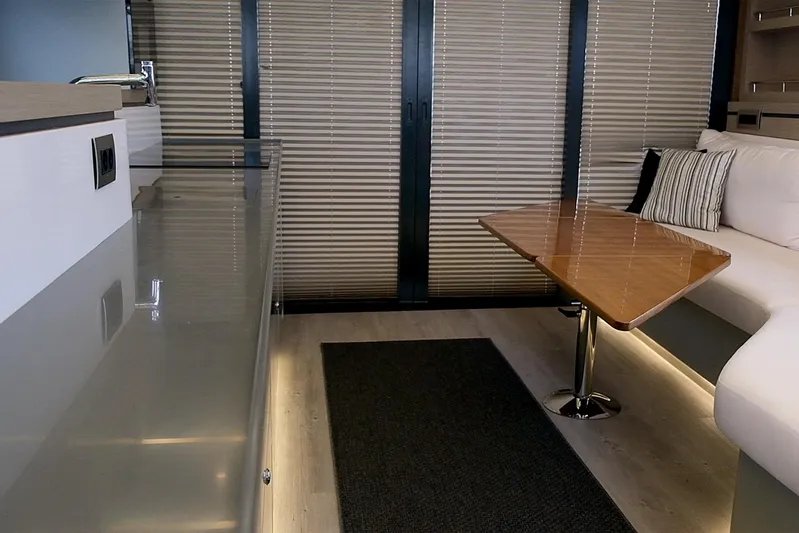  Yacht Photos Pics Modern yacht interior with sleek design, featuring a wooden table, sofa, and blinds. Custom DG CAT 43, 2023.