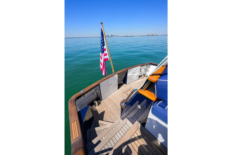 Aventurer Yacht Photos Pics Deck view of 1986 Jongert 85 yacht with American flag, calm sea, and distant cityscape.