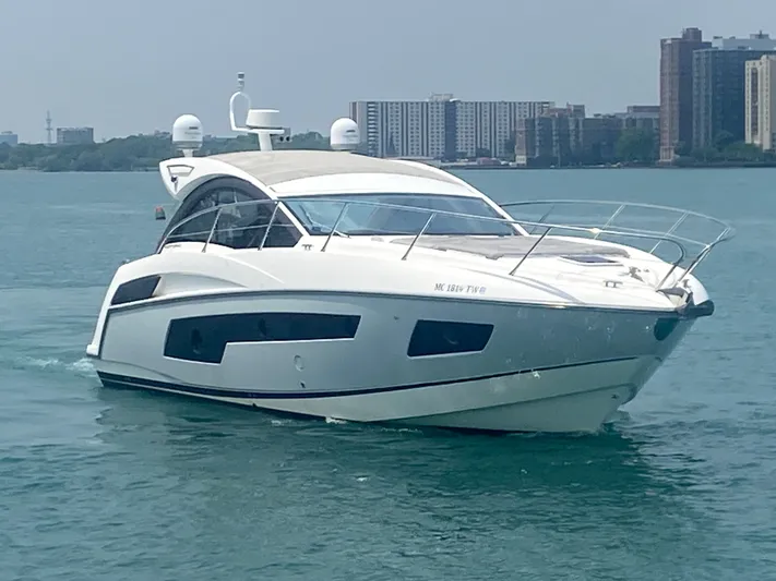 Work Hard, Play Hard Yacht Photos Pics 2013 Sunseeker Portofino 40 yacht cruising on a calm waterway near city skyline.