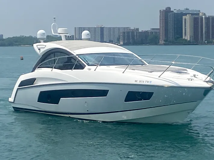 Work Hard, Play Hard Yacht Photos Pics 2013 Sunseeker Portofino 40 yacht cruising on water with city skyline backdrop.