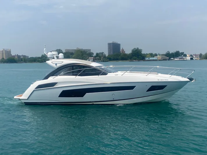 Work Hard, Play Hard Yacht Photos Pics 2013 Sunseeker Portofino 40 yacht cruising on calm waters near a cityscape.