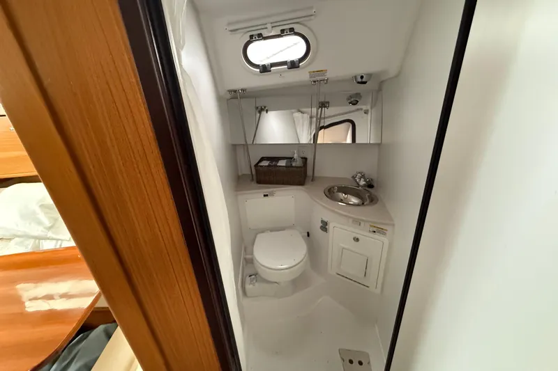  Yacht Photos Pics 2023 Catalina 315 yacht bathroom with toilet, sink, and porthole window.