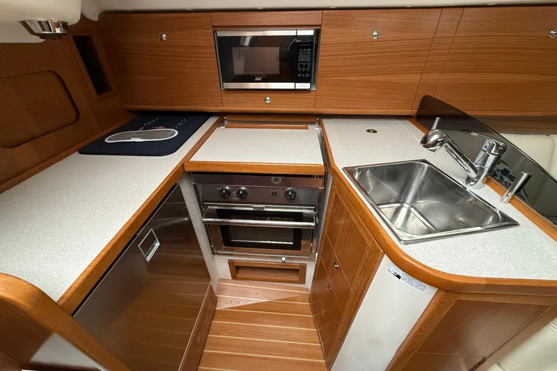  Yacht Photos Pics 2023 Catalina 315 yacht kitchen with modern appliances and wooden cabinetry.