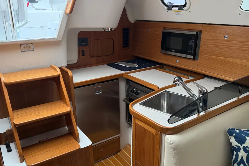  Yacht Photos Pics Modern kitchen in 2023 Catalina 315 yacht with wood cabinetry, sink, microwave, and stairs.