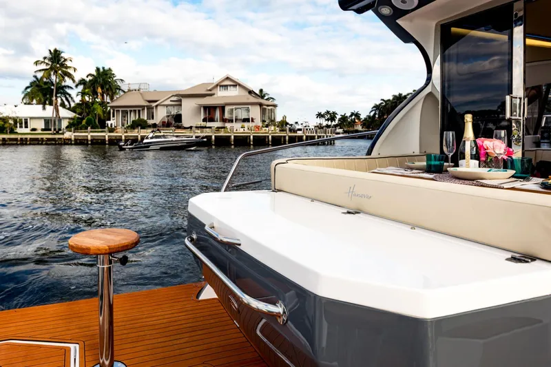 Custom Order Your 415 Today! Yacht Photos Pics Luxurious Hanover 415 yacht with elegant dining setup, cruising near waterfront homes, 2025 model.