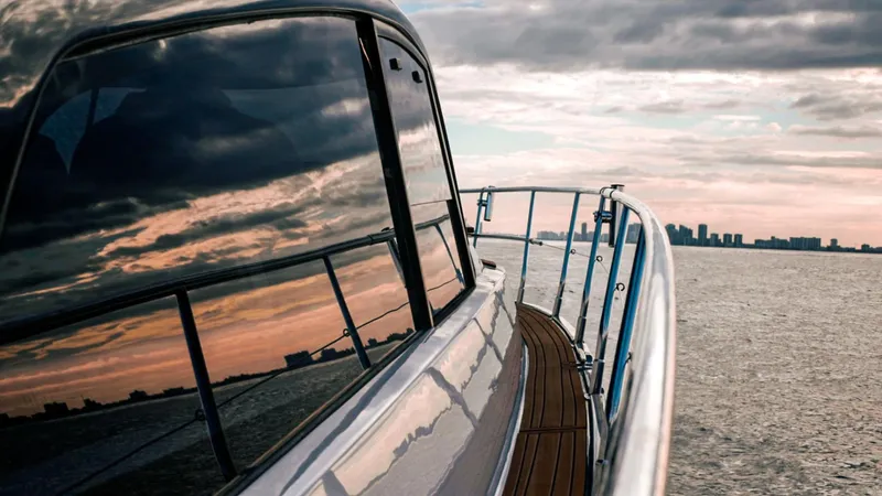 Custom Order Your 415 Today! Yacht Photos Pics Sleek Hanover 415 yacht cruising at sunset, reflecting city skyline on water.