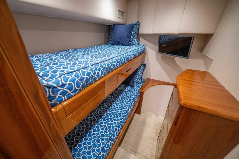 Watts Up Yacht Photos Pics 2016 Viking 66 Convertible yacht cabin with blue patterned bunk beds and wooden cabinetry.