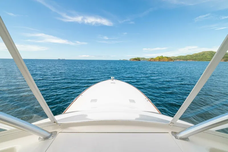 Watts Up Yacht Photos Pics Bow view from 2016 Viking 66 Convertible yacht on open sea with distant islands.