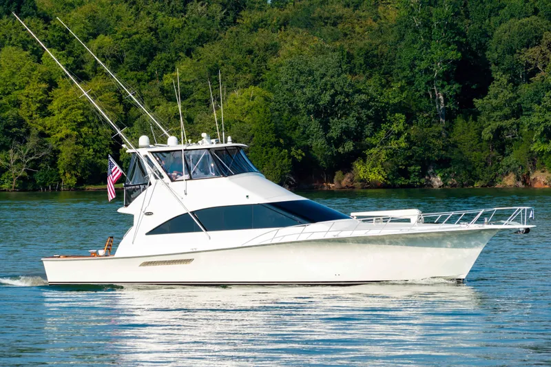  Yacht Photos Pics 1997 Ocean Yachts 60 Sport Fish cruising on a serene lake with lush green trees.