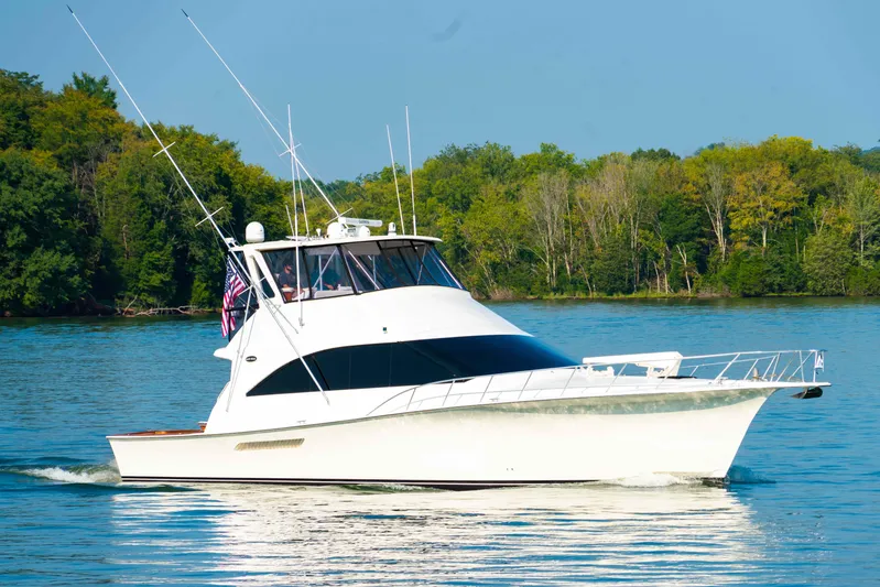  Yacht Photos Pics 1997 Ocean Yachts 60 Sport Fish cruising on a serene lake with lush green trees.
