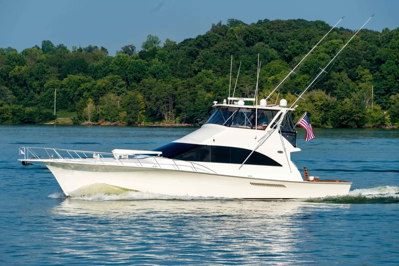  Yacht Photos Pics 1997 Ocean Yachts 60 Sport Fish cruising on a serene lake with lush green backdrop.