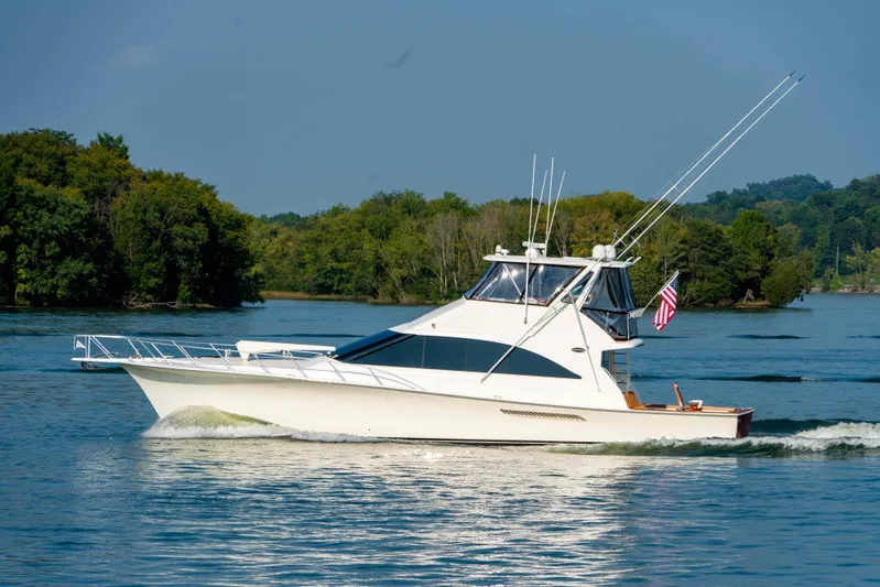  Yacht Photos Pics 1997 Ocean Yachts 60 Sport Fish cruising on a serene lake with lush green trees.
