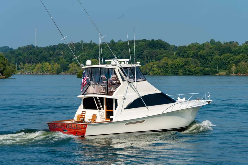  Yacht Photos Pics 1997 Ocean Yachts 60 Sport Fish cruising on a serene lake with lush green backdrop.