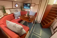 Cozy yacht interior with red seating, wooden table, and TV, aboard Custom Survey 55, 1997 model.