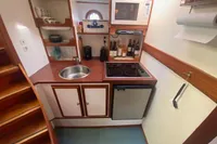 Compact boat kitchen with sink, stove, microwave, and storage shelves in a Custom Survey 55, 1997 model.