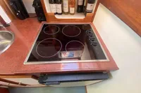 Modern kitchen with electric stovetop and wine bottles on a Custom Survey 55, 1997 model.