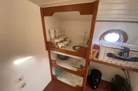 Cabin interior of 1997 Custom Survey 55 with wooden shelves and nautical decor.