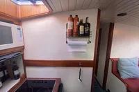 Interior of 1997 Custom Survey 55 yacht kitchen with stove, microwave, and shelf with bottles.