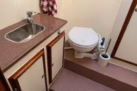 Compact boat bathroom with sink, toilet, and storage in Custom Survey 55, 1997 model.