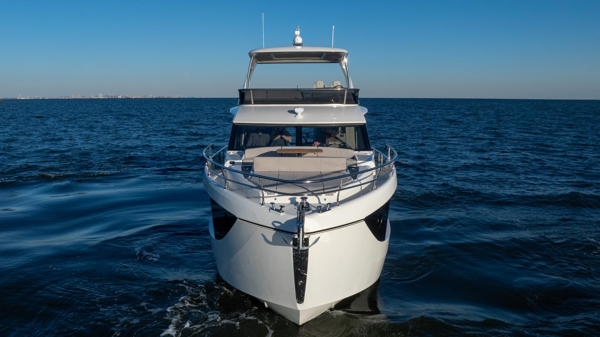 2025 Absolute 60 Fly yacht cruising on open sea under clear blue sky.