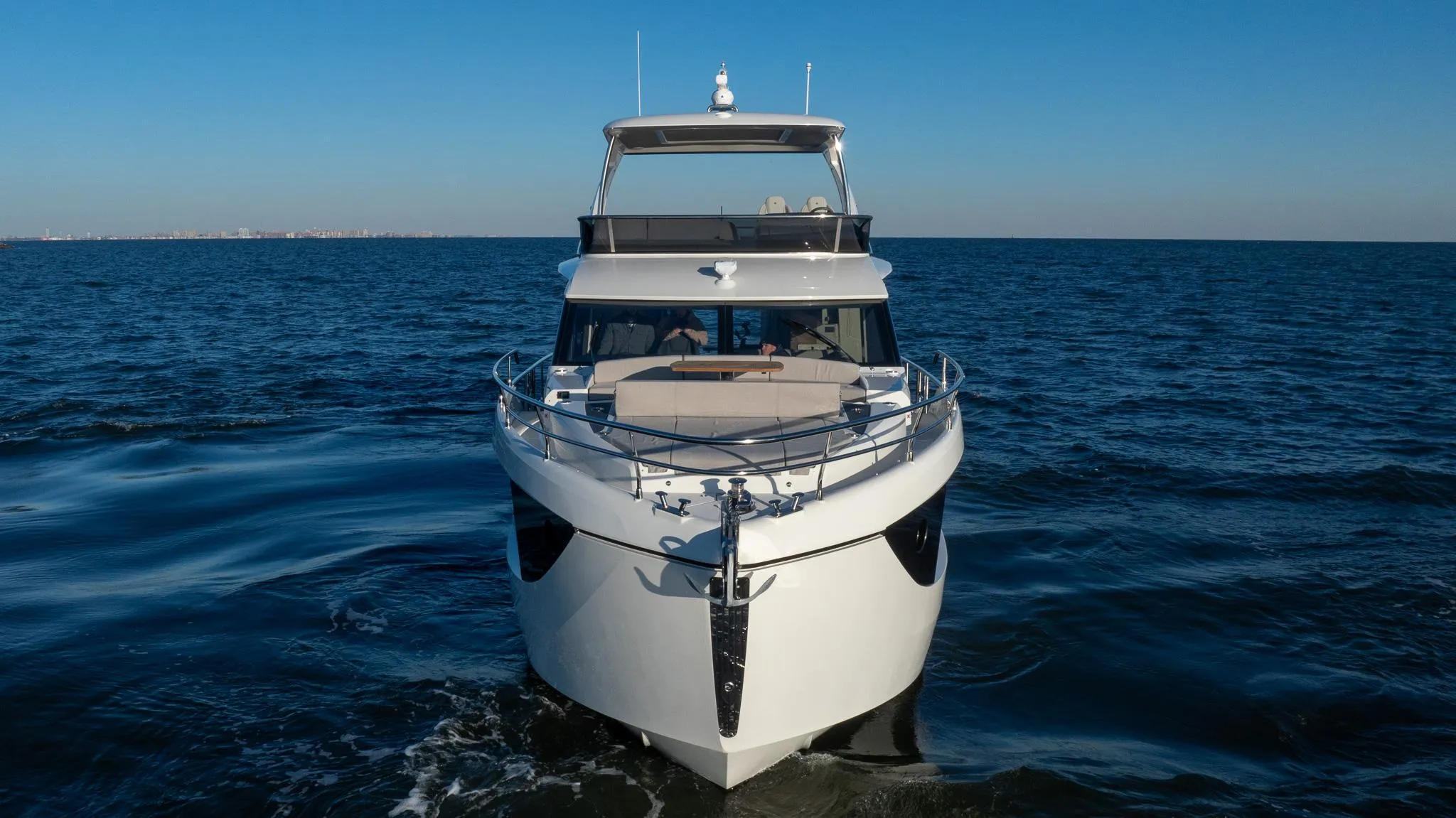 2025 Absolute 60 Fly yacht cruising on open sea under clear blue sky.