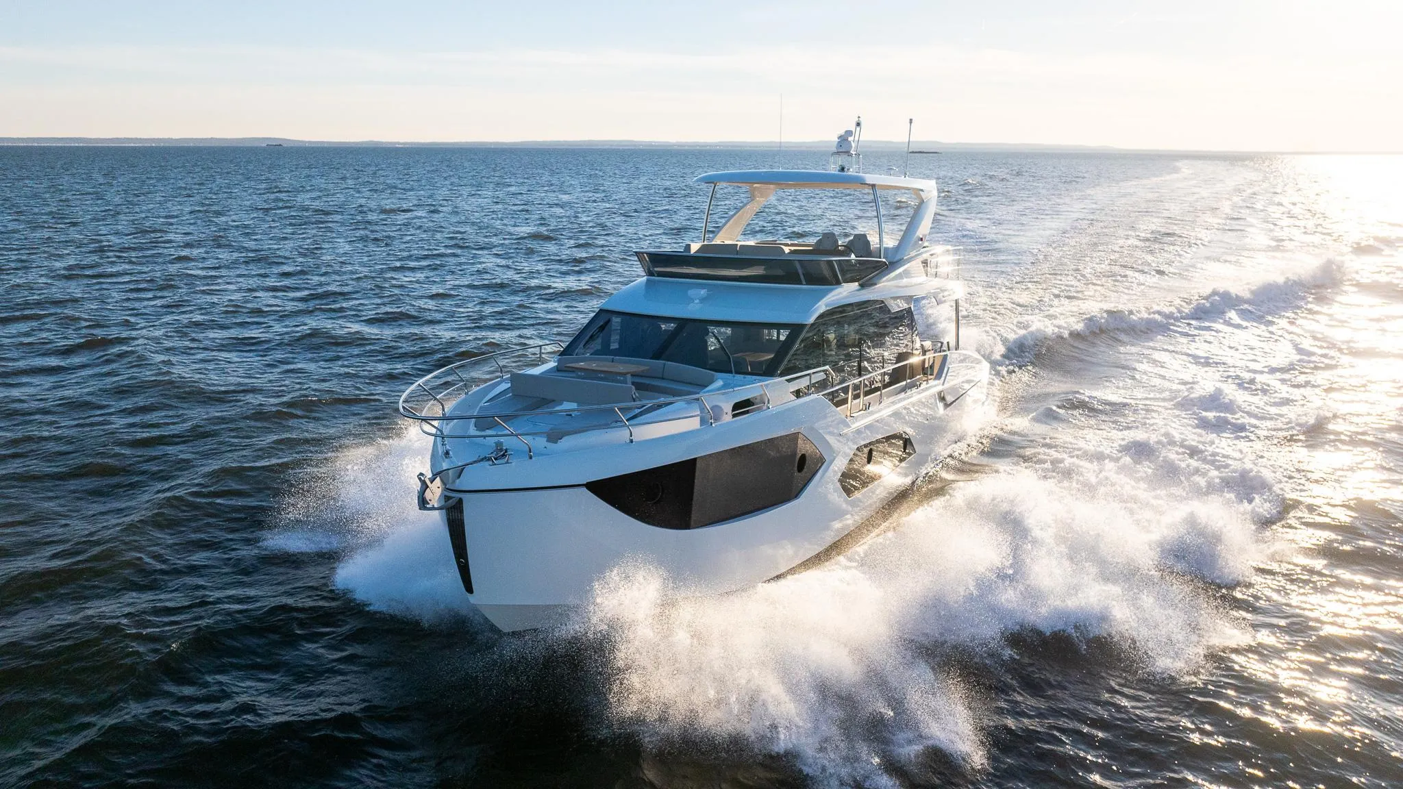 2025 Absolute 60 Fly yacht cruising on open water at sunset.