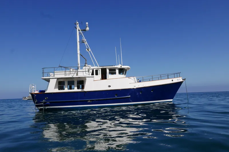 Blue Yacht Photos Pics 1989 Nordhavn 46 yacht on calm sea under clear blue sky.