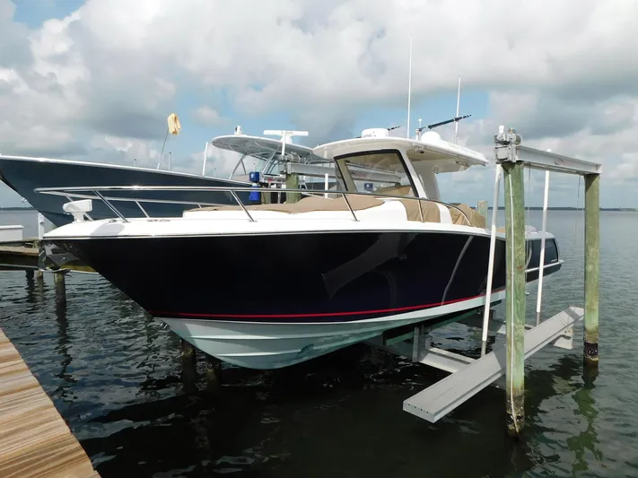Happily Ever After Yacht Photos Pics 2016 Belzona 327 WA boat on lift, docked under cloudy sky.