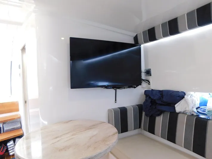 Happily Ever After Yacht Photos Pics Interior of 2016 Belzona 327 WA with TV, striped seating, and round table.