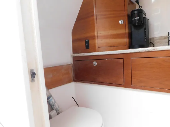 Happily Ever After Yacht Photos Pics Compact bathroom in 2016 Belzona 327 WA boat with wooden cabinetry and a coffee maker.