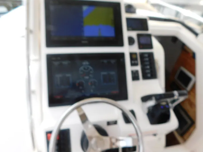Happily Ever After Yacht Photos Pics Control panel of a 2016 Belzona 327 WA boat with navigation screens and steering wheel.