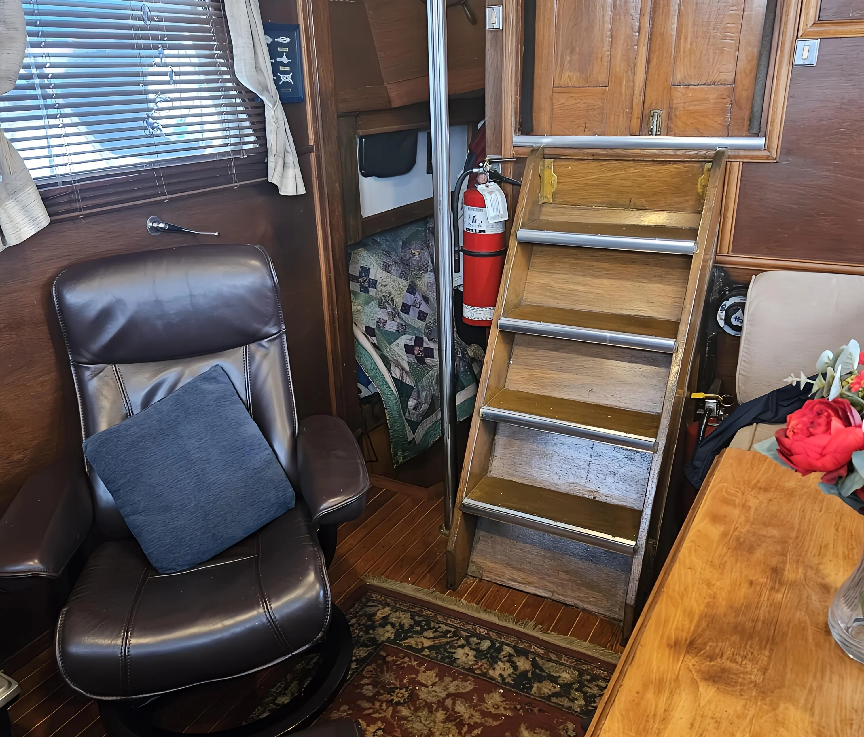 Interior of 1969 Rhodes Motorsailer Steel Ketch with leather chair, wooden stairs, and nautical decor.