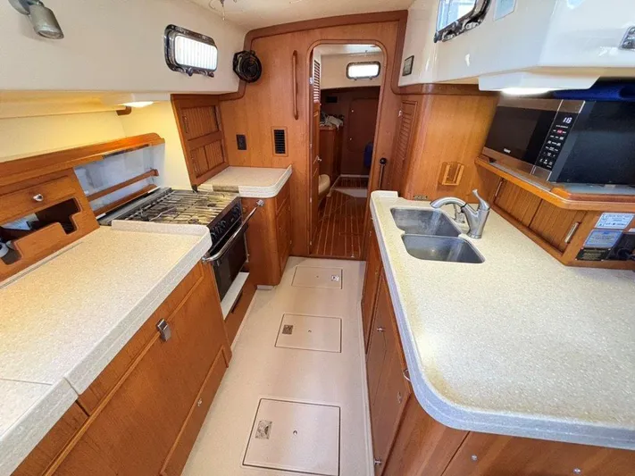 Calliope Yacht Photos Pics 2007 Island Packet 485 yacht interior kitchen with stove, sink, and wooden cabinetry.