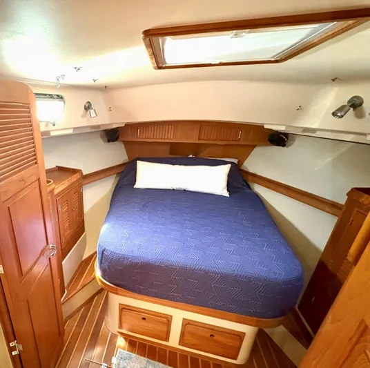 Calliope Yacht Photos Pics Cozy cabin interior of 2007 Island Packet 485 yacht with wooden furnishings and blue bedding.