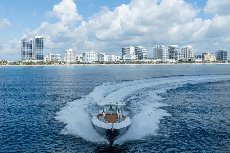 Sun Owl Yacht Photos Pics 2020 HCB 42 Lujo boat cruising near city skyline under cloudy sky.