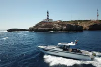 Nimbus T11 boat cruising near a rocky coastline with a lighthouse, 2022 model.