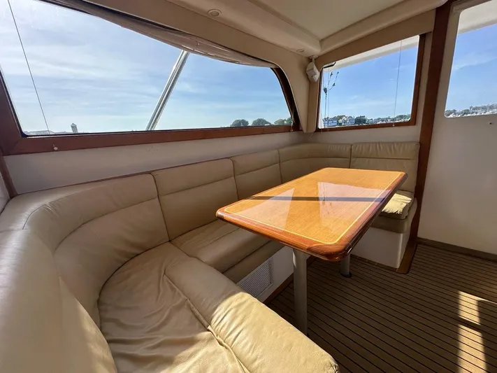 Lola Yacht Photos Pics Interior of 2005 Cabo 35 Flybridge with leather seating and wooden table.