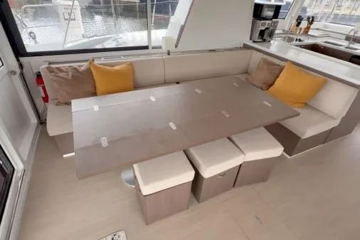 Joy Yacht Photos Pics Modern Bali 5.4 yacht interior with dining area, beige seating, and yellow cushions, 2021 model.