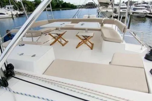 Joy Yacht Photos Pics 2021 Bali 5.4 yacht deck with seating and tables, docked at a marina.