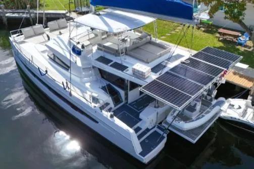 Joy Yacht Photos Pics 2021 Bali 5.4 catamaran with solar panels docked by lush greenery.