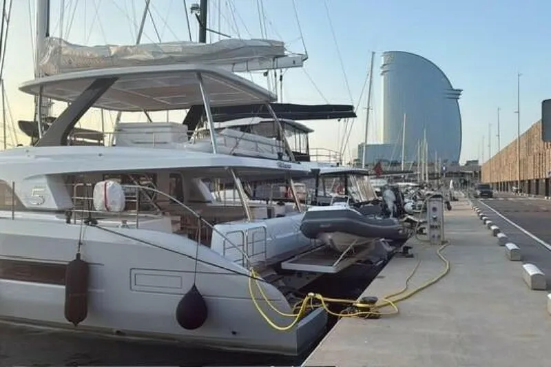 Olivia 007 Yacht Photos Pics 2025 Lagoon 65 yacht docked at marina with modern architecture in background.